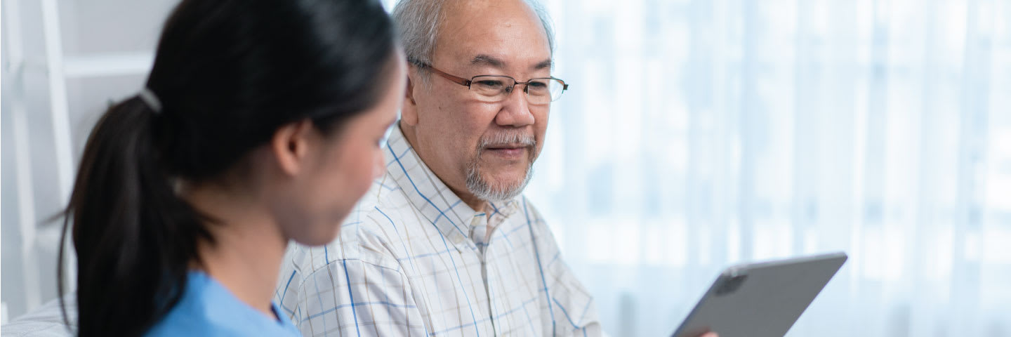 A senior man and a younger woman reviewing Medicare information on a tablet