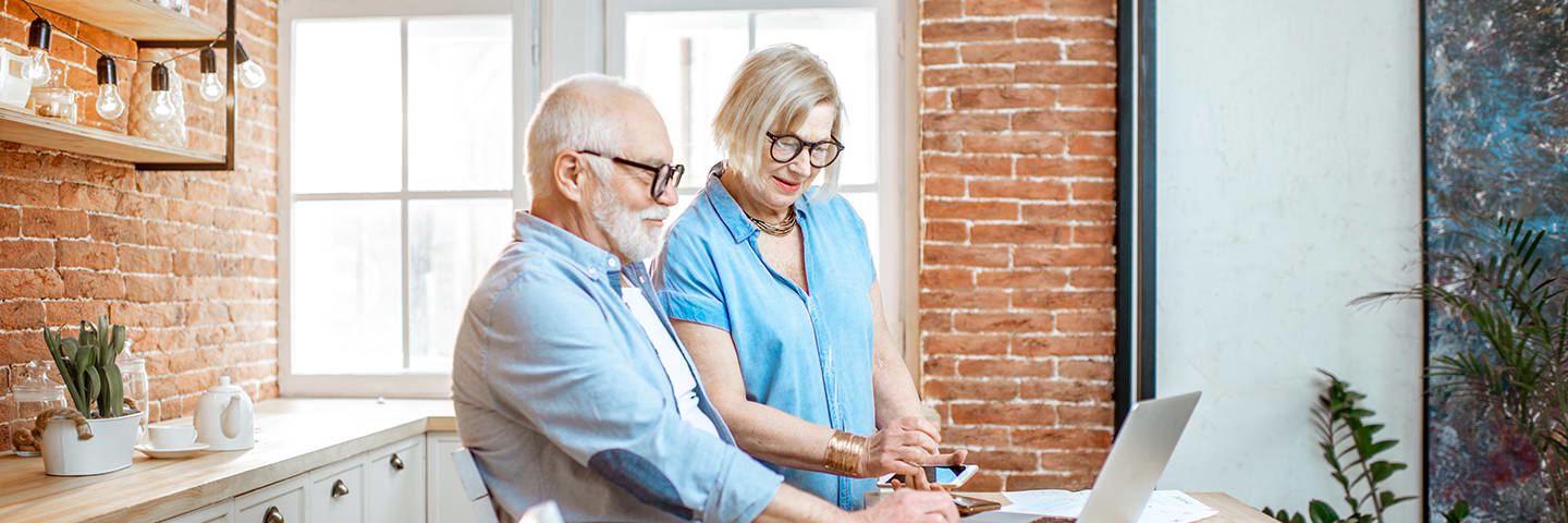 Seniors looking at computer in kitchen together