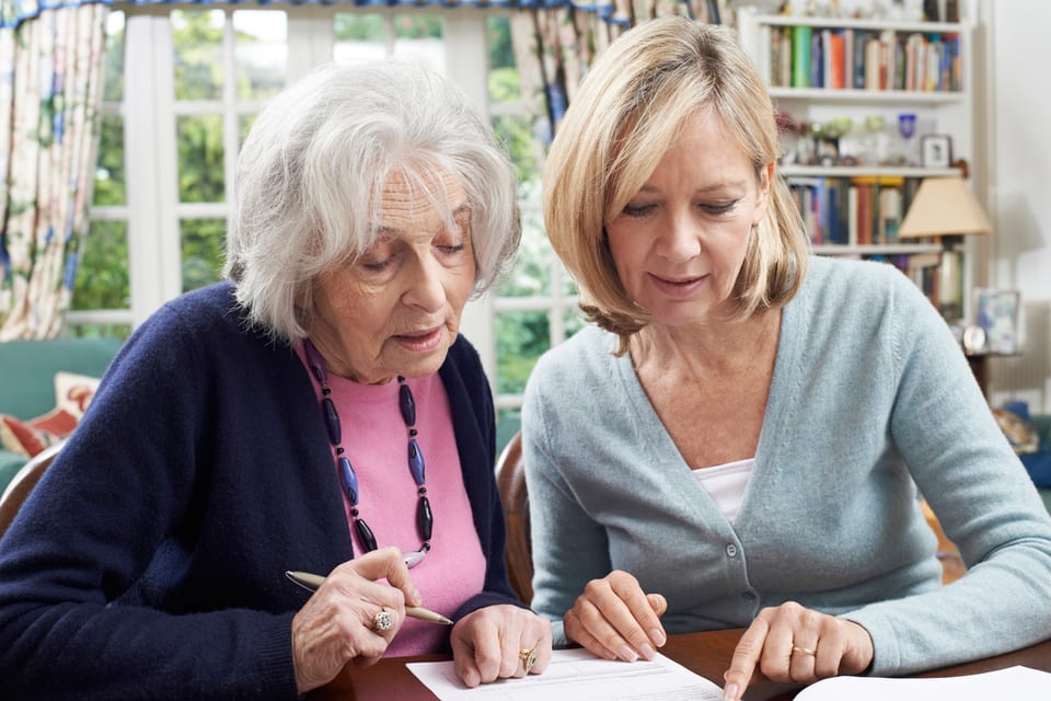 A senior woman and a middle-aged woman filling out forms